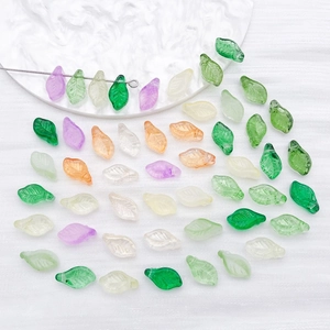 Macro detail of colorful leaf-shaped glass charms with textured veins on white stone