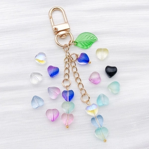 Detailed macro view of colorful heart-shaped glass beads and leaf charm on a key chain