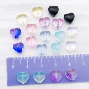 Colorful transparent heart-shaped glass beads set on white fabric with a ruler guide