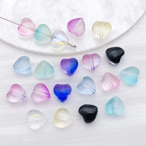 Close-up of colorful heart-shaped glass beads for DIY jewelry making on a white tray