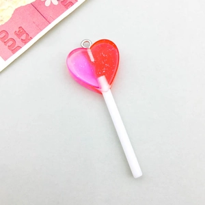 Close-up of heart-shaped lollipop charm with glitter resin and red-pink gradient detail