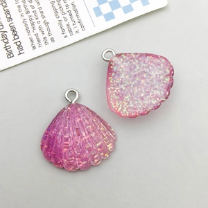 Detailed view of pink glitter resin shell charms with silver metal rings for DIY jewelry