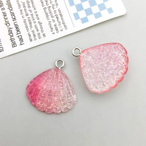 Close-up of pink glitter resin shell charms for DIY jewelry making with silver rings
