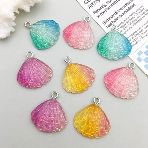 Close-up of eight glittery resin shell charms in gradient colors with silver jump rings
