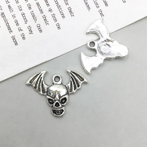 Nahaufnahme von zwei Vintage-Silber-Totenkopf-Fledermaus-Anhängern mit Flügeltexturen
