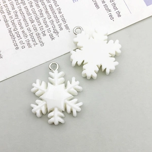 Detailed view of white snowflake resin charms with silver rings for DIY jewelry making