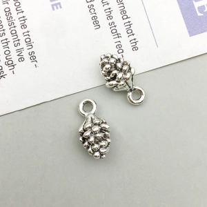 Close-up of realistic silver pine cone pendants with textured scales for DIY jewelry
