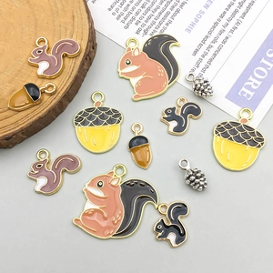 Cute enamel squirrel and acorn charms for DIY jewelry making displayed on a rustic background