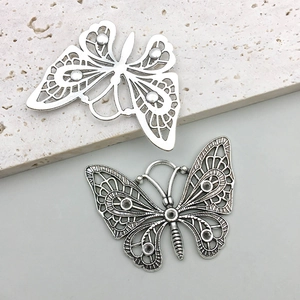 Detailed view of hollow butterfly charms in polished silver and vintage metal finishes