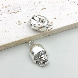Detailed macro view of two silver skull charms showing front and back hollow design