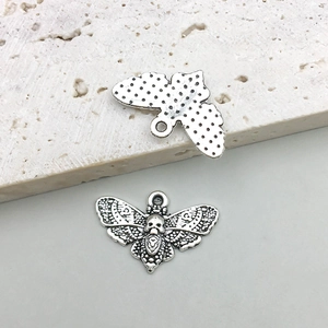 Macro shot of vintage silver butterfly pendant with skull engraving and dotted back texture