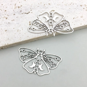 Macro shot of two vintage hollow moth pendants with crescent moon and gothic engravings