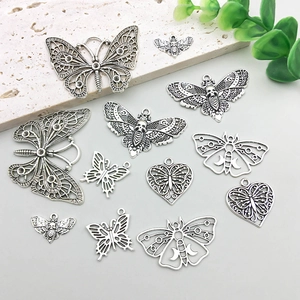 Detailed view of vintage silver butterfly and heart alloy pendants for DIY jewelry making