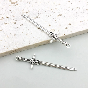 Detailed macro view of vintage silver sword pendants with intricate embossed patterns