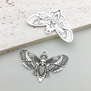 Close-up of vintage moth charms with skull detail and hollow wing patterns