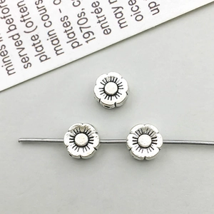 Macro detail of three retro flower-shaped silver alloy spacer beads for DIY jewelry making