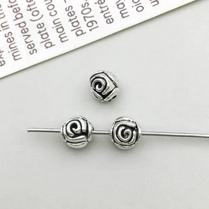 Macro shot of antique silver alloy beads with detailed rose pattern for DIY jewelry