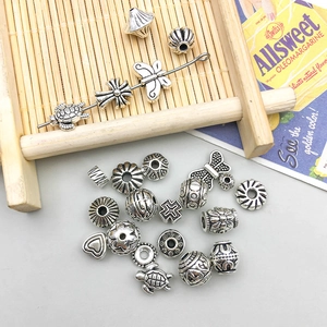 Dettaglio macro di perle in lega argento antico con motivi a cuore e tartaruga DIY