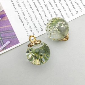 Close-up of glass bottle charms with dried gypsophila flowers and golden metal caps