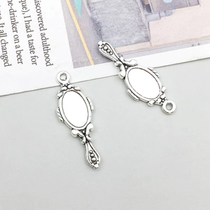 Detail of vintage silver hand mirror charms with embossed patterns for DIY jewelry making