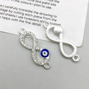 Detail van zilveren infinity bedeltjes met blauw emaille oog en glimmende kristallen