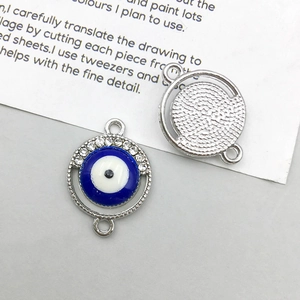 Detail van boze oog hangers van zilverlegering met blauw email en witte strassteentjes