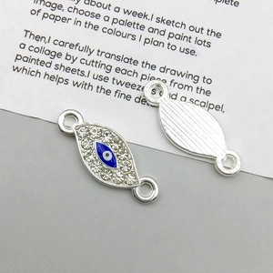 Detail van zilveren boze oog hanger met blauwe emaille afwerking en kristallen