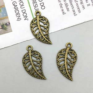 Detailed view of vintage bronze hollow leaf charms for DIY jewelry making and crafts