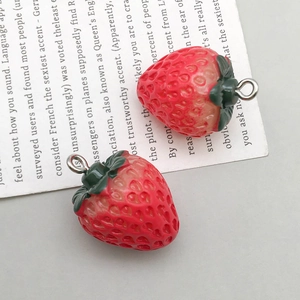 Close-up of two realistic resin strawberry charms with silver hooks for DIY jewelry making