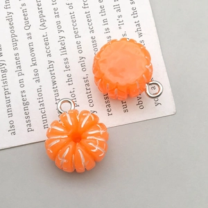 Top-down view of resin orange pumpkin pendants with fine white textures for DIY jewelry