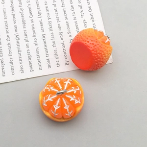 Detailed view of realistic orange and pulp resin charms for DIY jewelry making