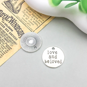 Makroaufnahme der runden Silber-Anhänger mit Gravur 'Love and Beloved' für DIY Schmuckdesign