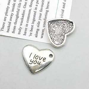 Detail of silver heart pendant with I love you engraving and hammered texture for DIY jewelry