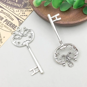 Detailed view of two vintage silver alloy key pendants with ornate baroque openwork patterns
