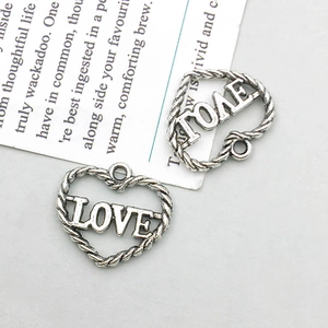 Detail of vintage silver heart pendants with LOVE cutout and twisted rope texture design