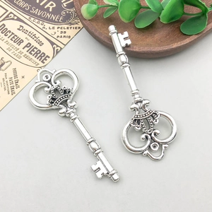 Detail of vintage silver alloy key charms with crown and vine motifs on a rustic tray