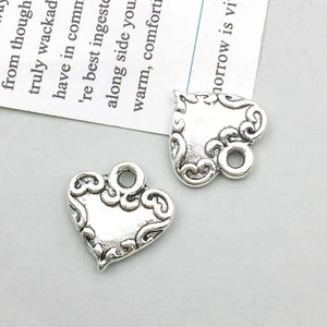 Macro view of vintage silver heart pendants with intricate filigree patterns for DIY jewelry