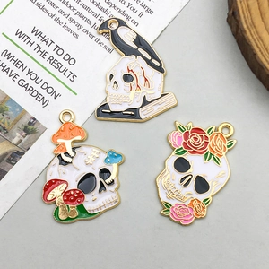 Detail of three gothic enamel skull charms with mushrooms, flowers, and raven designs