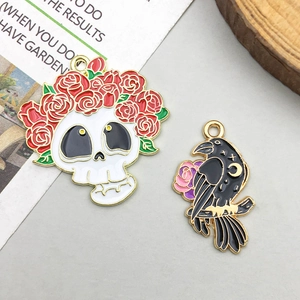 Detail of Halloween charms featuring a skull with roses and a crow with celestial motifs