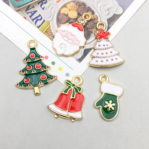 Dettaglio di cinque ciondoli natalizi smaltati con Babbo Natale e campane per gioielli fai da te