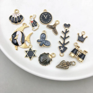Detailed close-up of mixed black and gold enamel charms for DIY jewelry in a ceramic dish