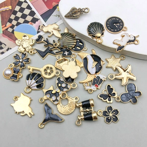 Close-up of mixed black and gold enamel charms with sea shells and nautical motifs