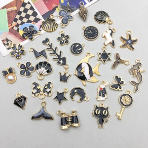 Flat lay of diverse black and gold alloy charms including mermaid tails and sea life