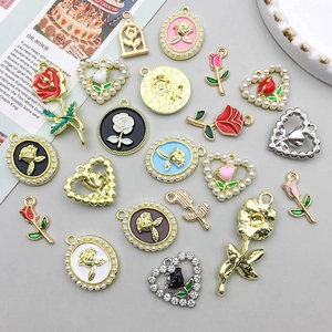 Macro view of assorted alloy rose flower heart charms with enamel and faux pearl details