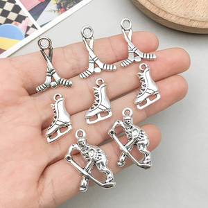 Pendentifs de hockey en argent antique avec patins et athlète présentés sur la main
