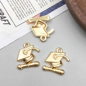 Detailed close-up of golden alloy graduation cap pendants with diplomas for DIY jewelry