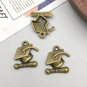 Macro detail of antique bronze graduation cap pendants with tassel for DIY jewelry making