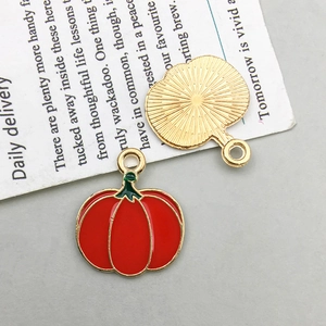 Nahaufnahme des roten Emaille-Kürbisanhängers mit goldener Rückseite für DIY-Schmuck
