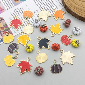 Bunte Emaille-Ahornblatt- und Kürbis-Anhänger für DIY-Schmuck auf dem Schreibtisch
