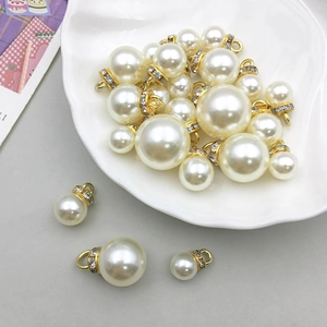 Detailansicht von künstlichen Perlenanhängern mit Gold-Strass-Kappen in einer Schale